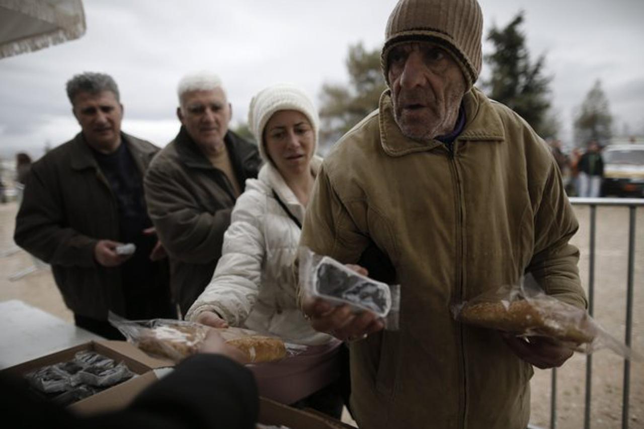 epa04633840 People line-up to receive olives and bread distributed for free by municipality of Athens during the celebrations of 'Clean Monday', on the Pnyx Hill, opposite the Acropolis Hill in Athens, Greece, 23 February 2015. Greece's SYRIZA-led governm