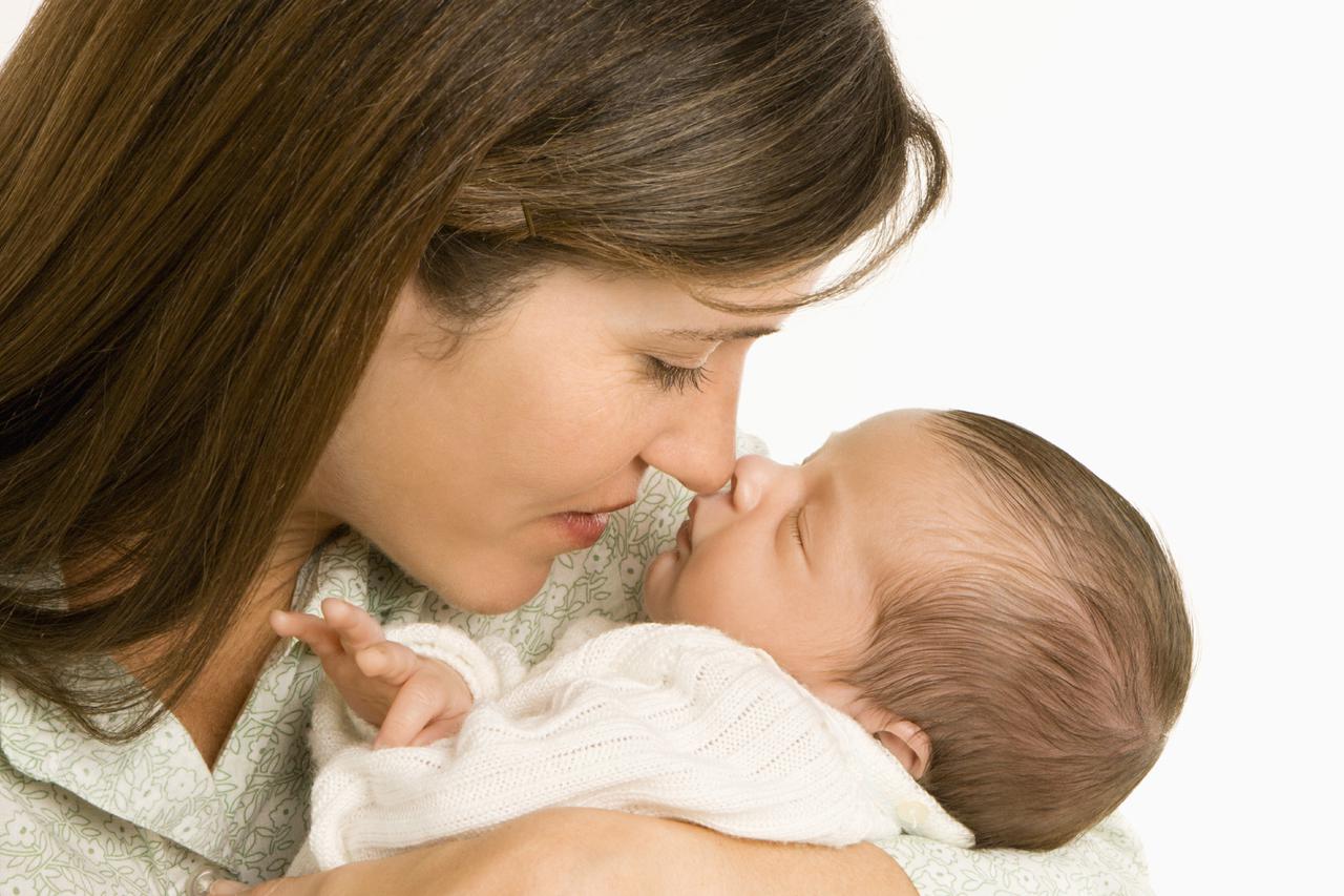 Mother nuzzling sleeping baby with nose and smiling.